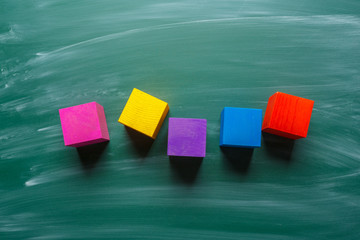 colored wooden cubes on green chalkboard