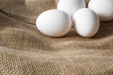 White eggs on the burlap bag in a rustic kitchen. Farm food concept.