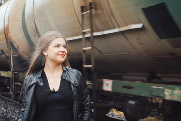 Fototapeta na wymiar Nice girl on a railway road near moving train
