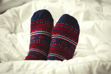   Against the backdrop of a white bed, female feet in socks