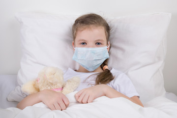 little girl is sitting in bed in a medical mask, to protect from infection