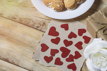 Small hearts on kraft paper. Cookies, gift box and white rose flower on a wooden background. Added effect