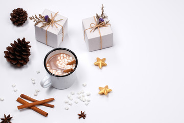 Cup of hot Chocolate drink with marshmallows, cinnamon sticks, anise star, gift and cones on white background. Winter christmas holiday background. Flat lay, Top view.