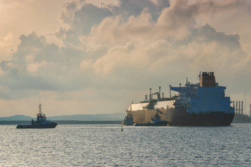 Obraz premium LNG TANKER- The big tanker maneuveres in the harbor secured by tugs 