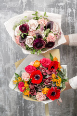 two beautiful luxury bouquet of mixed flowers in woman hand. the work of the florist at a flower shop