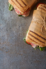 French baguette with sausage, tomatoes and lettuce. Dark background.