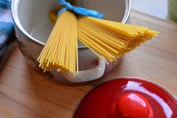 Uncooked spaghetti in the cooking pot at wooden table/ top view