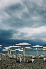 Wooden parasols and empty deckchairs on deserted beach on the off-season cloudy day