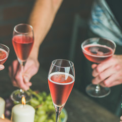 Holiday celebration table setting with food. Friends hands eating and drinking together. People having party, gathering, celebrating with rose champaign, square crop