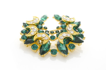 golden brooch with emeralds and diamonds isolated on white