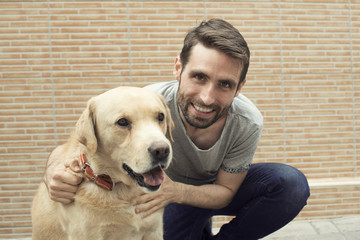 Retrato de hombre joven sonriente abrazando a un perro labrador
