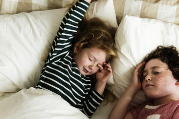 Fototapeta na wymiar A Caucasian siblings sleeping on the bed