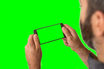 Young adult man hand hold green screen smartphone on green screen background.