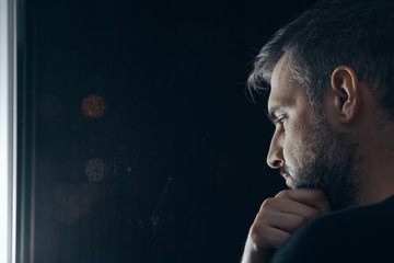Man holding chin beside window