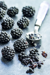 Mehrere Bromberen mit Löffel auf hellgrauem Hintergrund