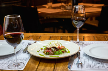 Traditional Italian specialty Burrata Cheese on ceramic plate served with olive oil and green salad over a white rustic wooden table.