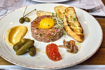fresh beef tartar with egg yolk, with mustard marmalade, anchovies and corn baguette.