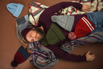 man lying between scattered hats