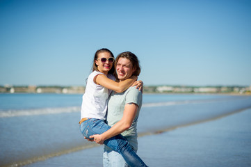 Fototapeta na wymiar On the seashore the guy holds the girl on hands.