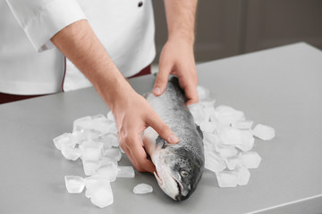 Chef putting fresh salmon on table in kitchen