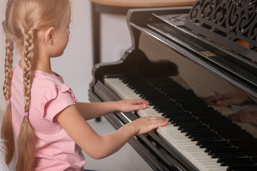 Little girl playing piano indoors