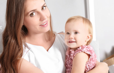 Young mother holding cute baby at home