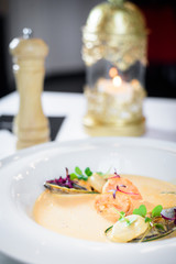 Plate of tasty cream of sea food soup with shrimps and mussels on table