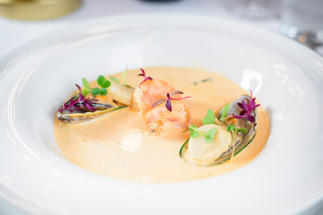 Plate of tasty cream of sea food soup with shrimps and mussels on table