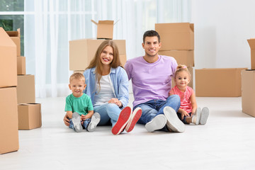 Fototapeta na wymiar Happy family sitting on floor near moving boxes in their new house