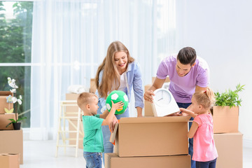 Happy family unpacking moving boxes in their new house