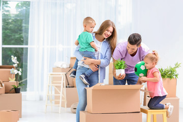 Fototapeta na wymiar Happy family unpacking moving boxes in their new house