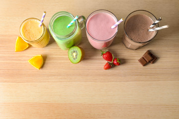 Different milkshakes in glassware on wooden background