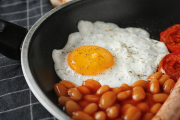 Frying pan with egg and beans on table