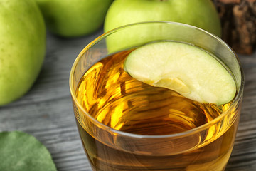 Glass with fresh apple juice on table, close up