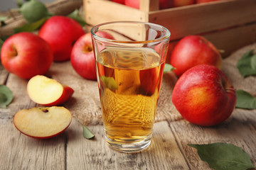 Glass with fresh apple juice on wooden table