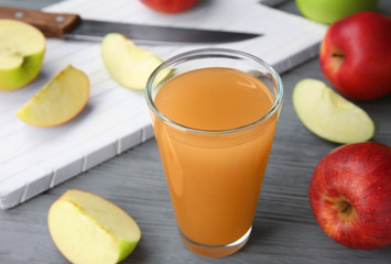 Glass with fresh apple juice on wooden table