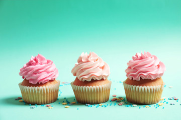 Many yummy cupcakes on color background