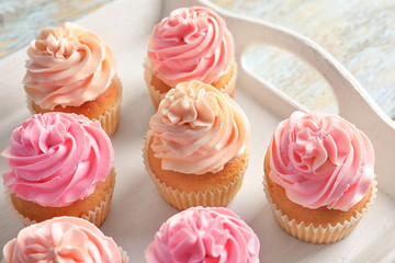 Tray with yummy cupcakes on wooden table