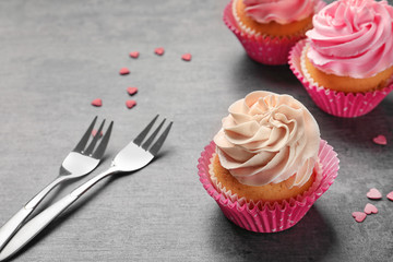Yummy cupcakes and forks on grey background