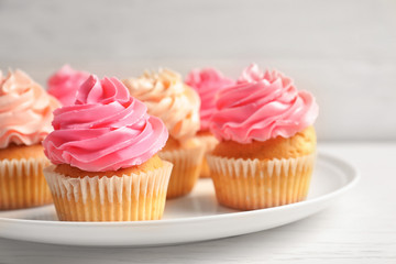 Plate with yummy cupcakes on wooden table