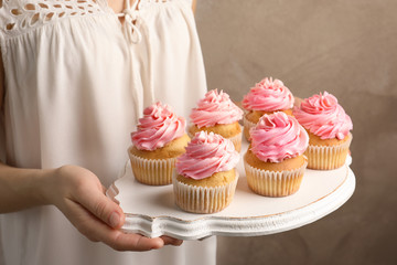 Woman holding board with delicious cupcakes