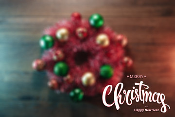 The inscription of Merry Christmas and Happy New Year, a wreath on a wooden brown table. Christmas card, holiday background. Mixed media.