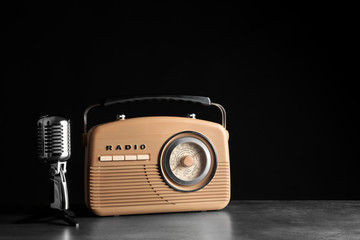 Retro radio and microphone on table against black wall