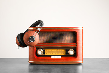 Retro radio and headphones on table against light wall