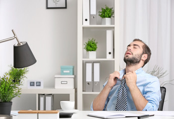 Young man feeling hot in office