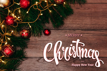 The inscription of Merry Christmas and Happy New Year, green spruce and chopping branches on a wooden brown table. Christmas card, holiday background. Mixed media.