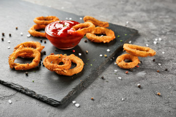 Fried onion rings with sauce on slate plate