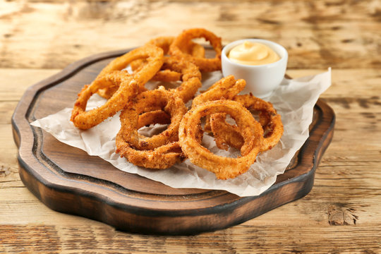 Fried onion rings with sauce on wooden board