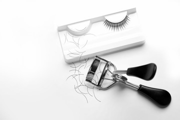 Curler and false eyelashes on white background