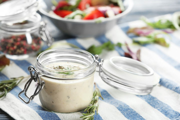Obraz na płótnie Canvas Jar with tasty sauce for salad on table